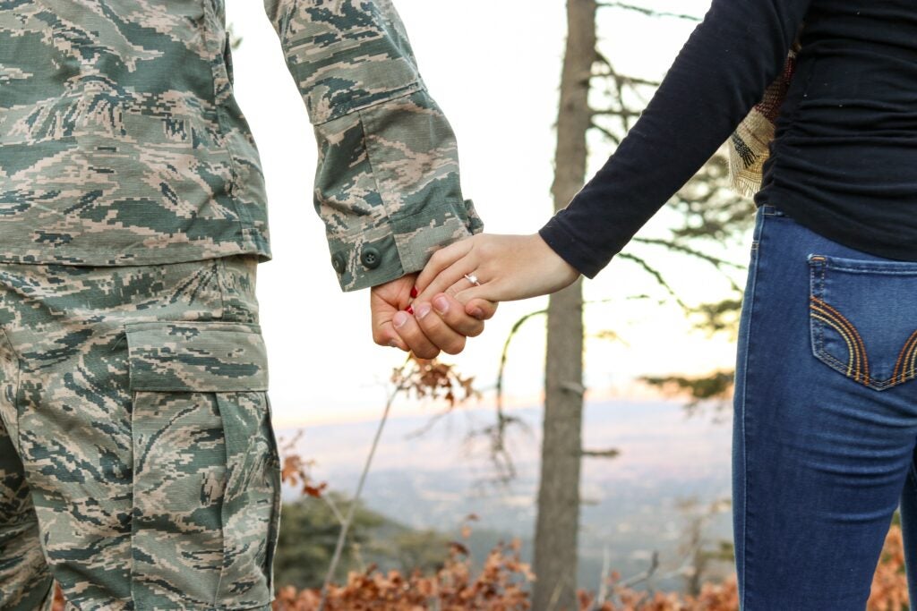 man in uniform holding wife's hand