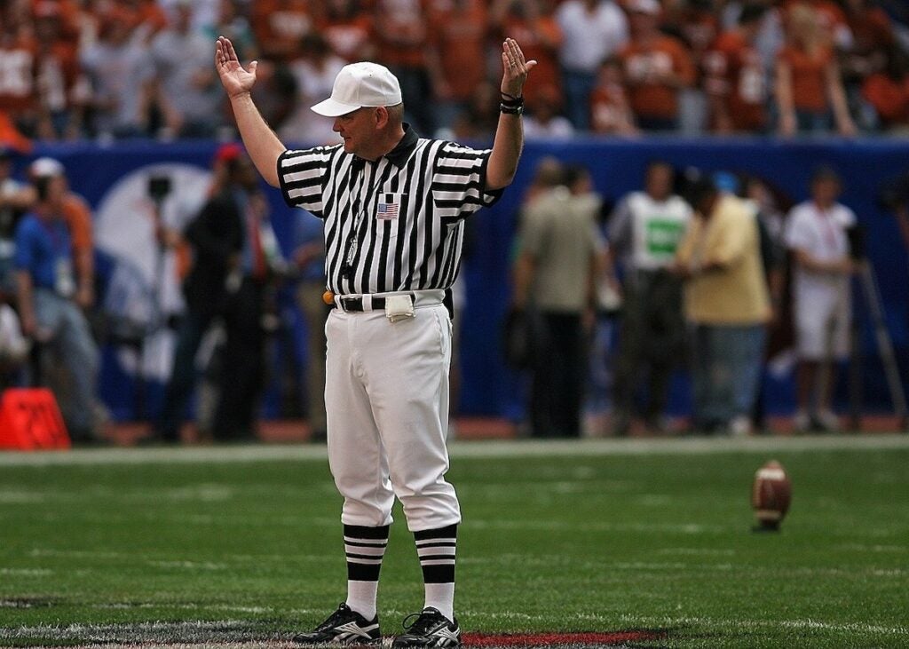 An NFL referee signaling the start of a new quarter. Refs no longer use pistols.
