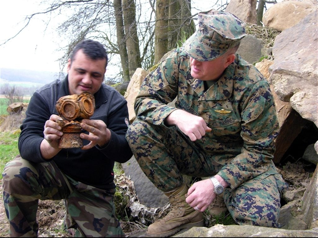 A historian showing a Marine a gas mask he found from WWII. Marine brigades today use different equipment.