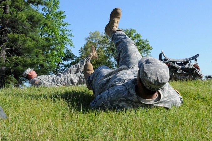 A soldier does PT while a drill sergeant looks on