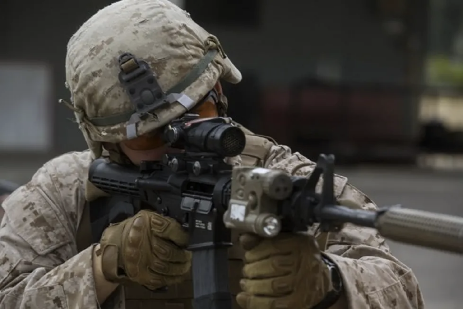 A service member aims a firearm with a suppressor.