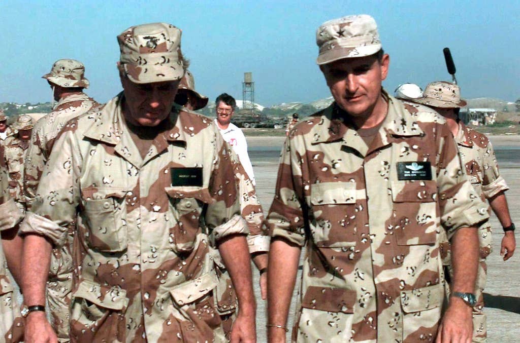 US President George Bush, left and wearing a desert camouflage BDU shirt and cap, walks toward the camera with US Air Force BGEN Thomas Mikolajcik, Commander AFFOR, right.  Other members of the Air Force as well as the media are seen in the background.  The President was visiting Somalia to witness first hand the efforts of Task Force Somalia that is in direct support of Operation Restore Hope.