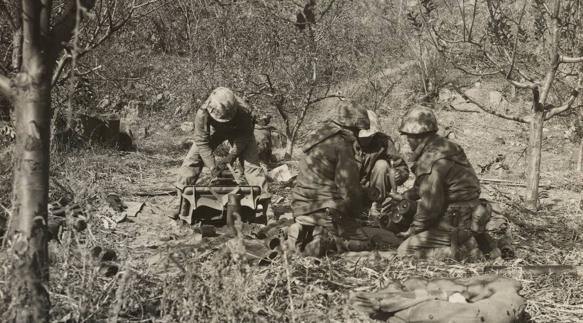 A Marine Corps weapons company section sets up their mortar to take communist positions under fire near Chosin Reservoir. Marine Corps photo