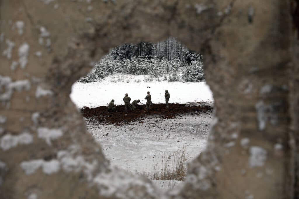 Photo of US Army combat engineers  pictured through a hole in a cement brick