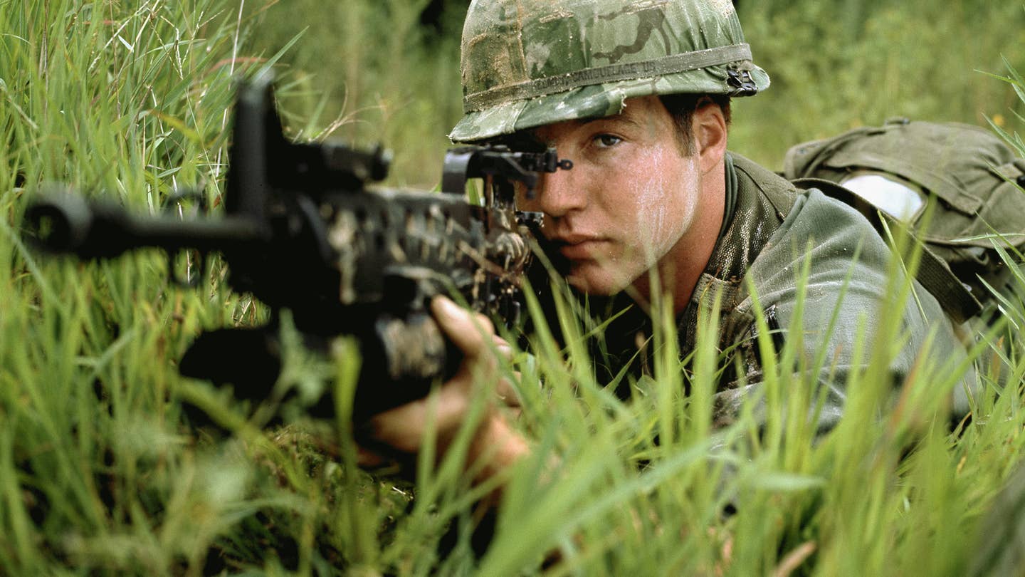 A US Army soldier aims an M16A1 rifle equipped with an M203 grenade launcher.