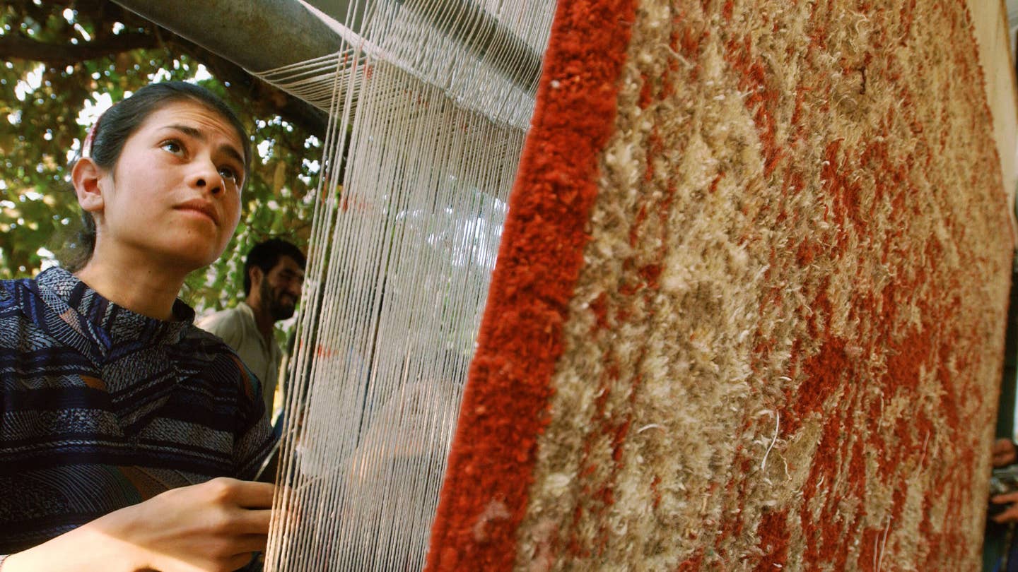 a woman looks at an Afghan war rug