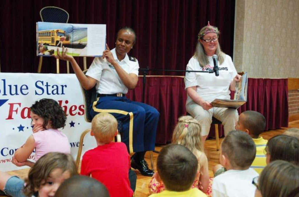During a Blue Star Families program June 22 at the Joint Base Myer-Henderson Hall Community Center, JBM-HH Commander Col. Fern O. Sumpter and Walt Disney Company official Tammy McFeggan take turns reading the book “Billy Twitters and His Blue Whale Problem” to children. (Photo By Rhonda Apple)