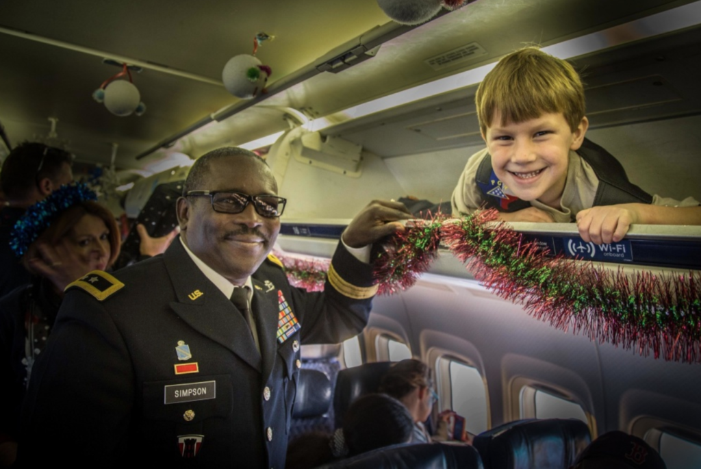 Maj. Gen. Lester Simpson, 36th Infantry Division commander, chats with Jason Thomas in the overhead baggage compartment during a charter flight from Fort Hood. Jason is the son of Staff Sgt. Ryan J. Thomas, who died while serving in the U.S. Air Force. The flight is part of the Snowball Express, a non-profit organization that brings the families of fallen members of the military to the Dallas/Fort Worth area each December. Each of the nine American Airlines charter aircraft were decorated for the mission and the standard in-flight rules were somewhat relaxed for the kids. (36th Infantry Division photo by Maj. Randy Stillinger/Released)