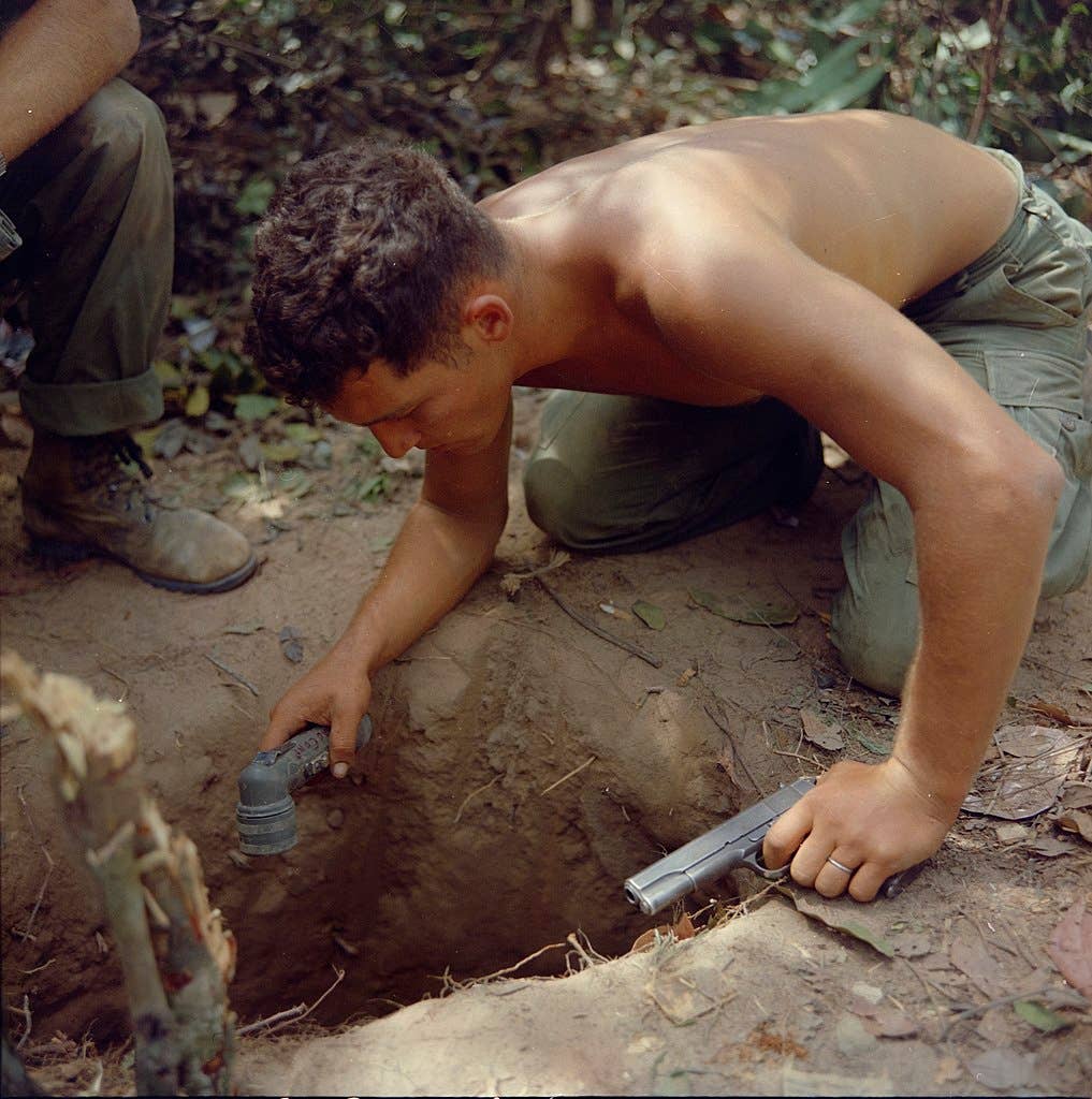 SGT Ronald A. Payne (Atlanta, Ga) Squad Leader, Company A, 1st Battalion, 5th Mechanized Infantry, 25th Infantry Division, checks a tunnel entrance before entering. This was one of several tunnels found in the Cu Chi, Republic of Vietnam area. This tunnel was found while the company was conducting a search and destroy mission as a part of Operation “Cedar Falls” in the Hobo Woods area. (National Archives)