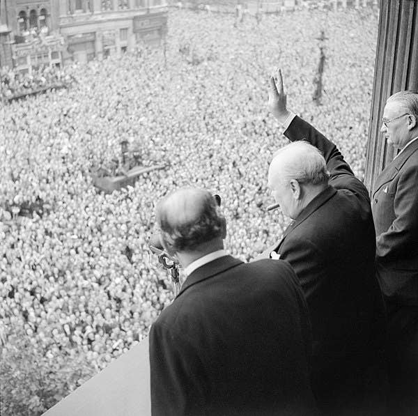 <a href="https://en.wikipedia.org/wiki/Winston_Churchill">Winston Churchill</a>&nbsp;waving to the crowds from Whitehall on 8&nbsp;May celebrating the end of the war, showing the V of Victory. Wikimedia Commons.