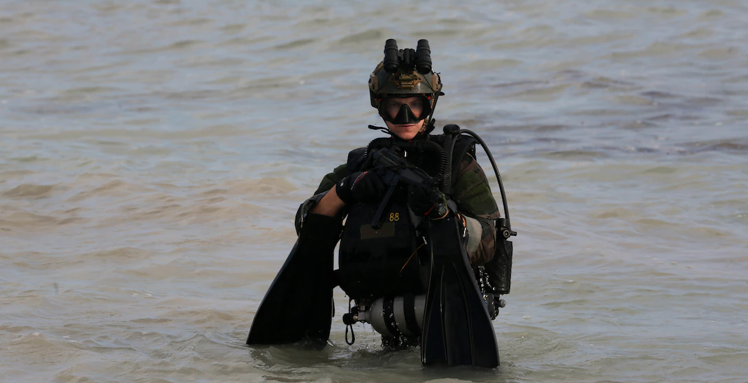 Feature image: A 1st Marine Special Operations Battalion critical skills operator surfaces from the ocean and advances up a beach, completing a combat dive exercise in Key West, Fla., Feb. 18, 2015. (DoD Photo).

