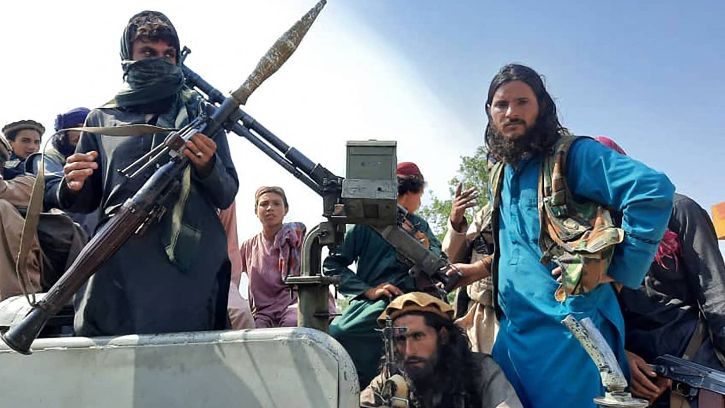 Taliban fighters sit over a vehicle on a street in Laghman province on August 15, 2021. (Photo/AFP via Getty Images)