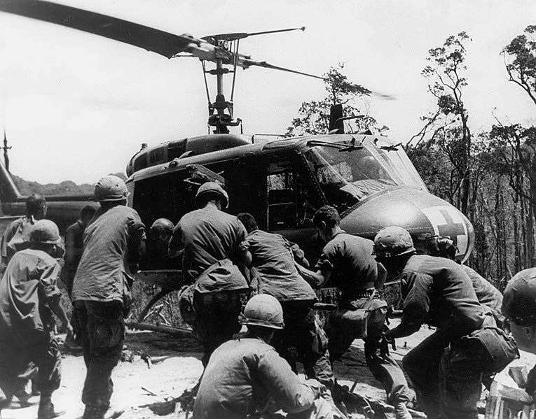 This image shows wounded Troopers being loaded onto a UH1H Aca,!A"HueyAca,!A? helicopter operating in a Aca,!A"Dust OffAca,!A? or medical evacuation role. Operation Apache Snow, May 1969. (Melvin Zais Photograph Collection). (Photo Credit: USAMHI)