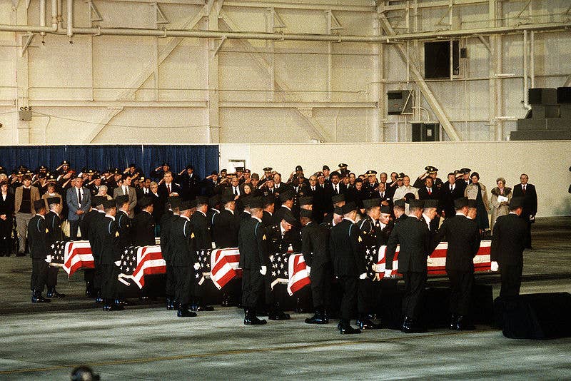 Mourners looks on as members of the 101st Airborne Division carry a casket containing the remains of members of the 3rd Bn., 502nd Inf., 101st Airborne Div., into a hangar for a memorial service. (Wikimedia Commons)