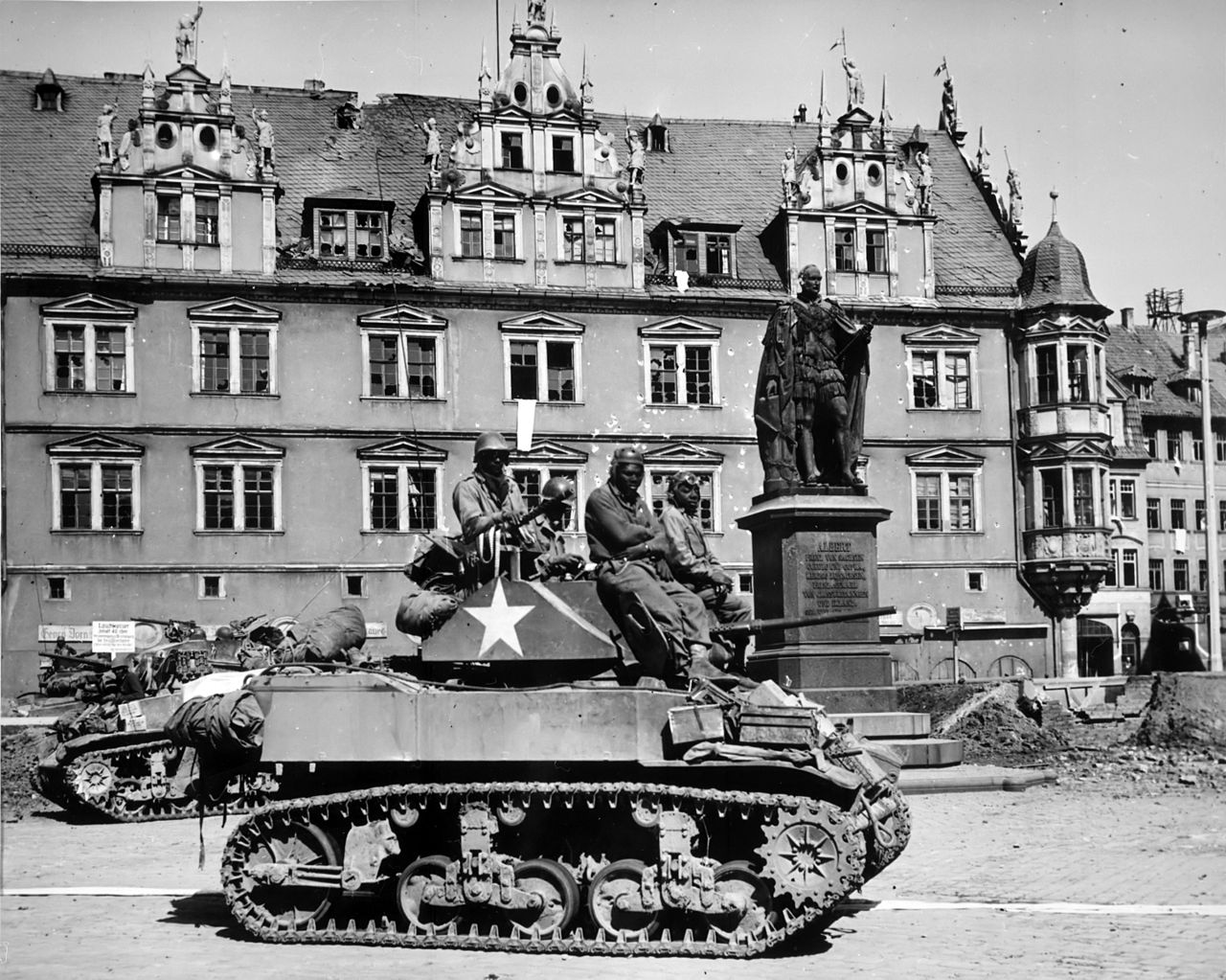Crews of U.S. M5 Stuart light tanks from Company D, 761st Tank Battalion, stand by awaiting call to clean out scattered Nazi machine gun nests in Coburg, Germany. (Wikimedia Commons)