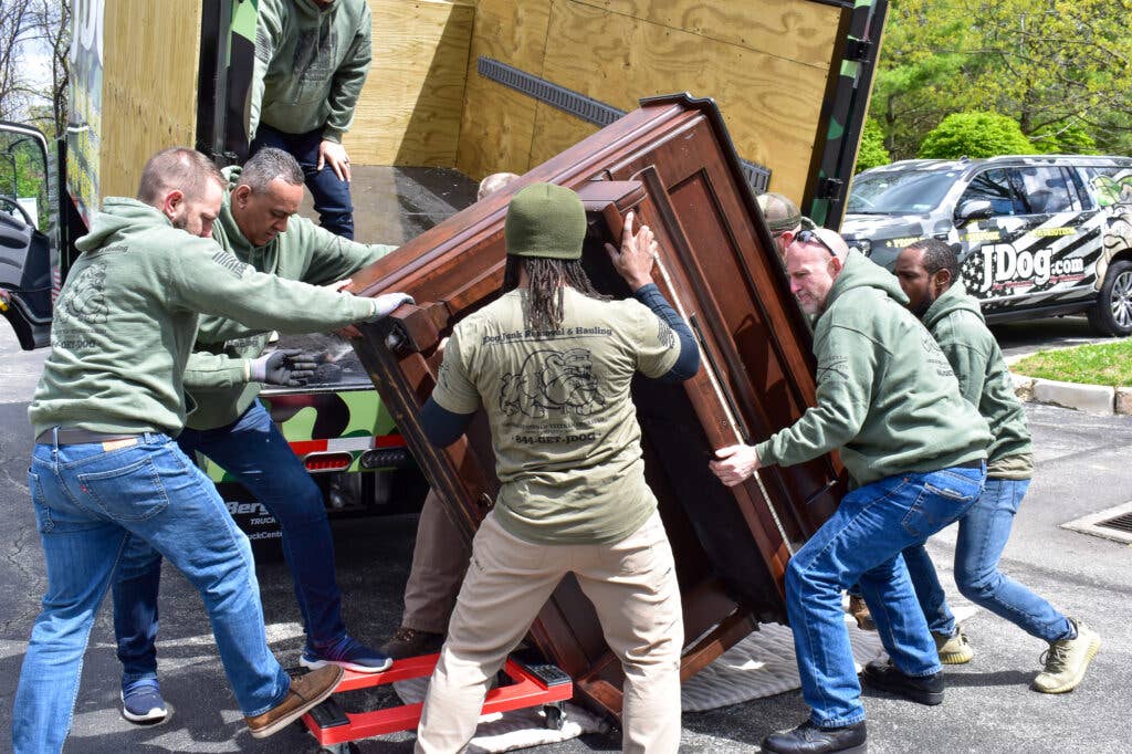 <em>JDoggers work together to haul away a piano (Operation Hidden Treasures)</em>