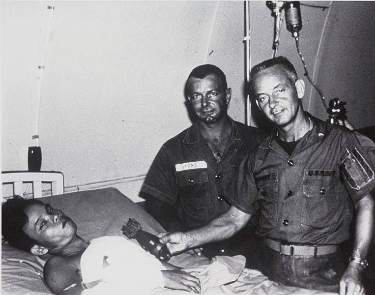 Nguyen Loung, ordnance expert John Lyons, and Dr. Dinsmore pose for the press following the surgery. (U.S. Navy Photo)