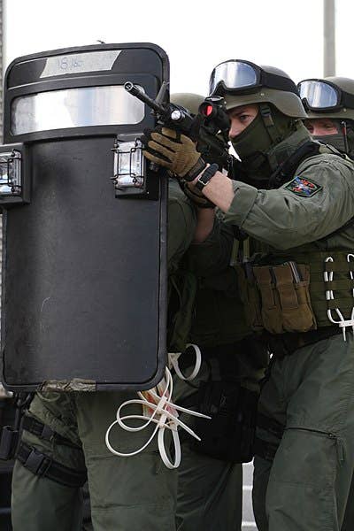 A ballistic shield with a clear armored viewing port and spotlights. (USMC photo)