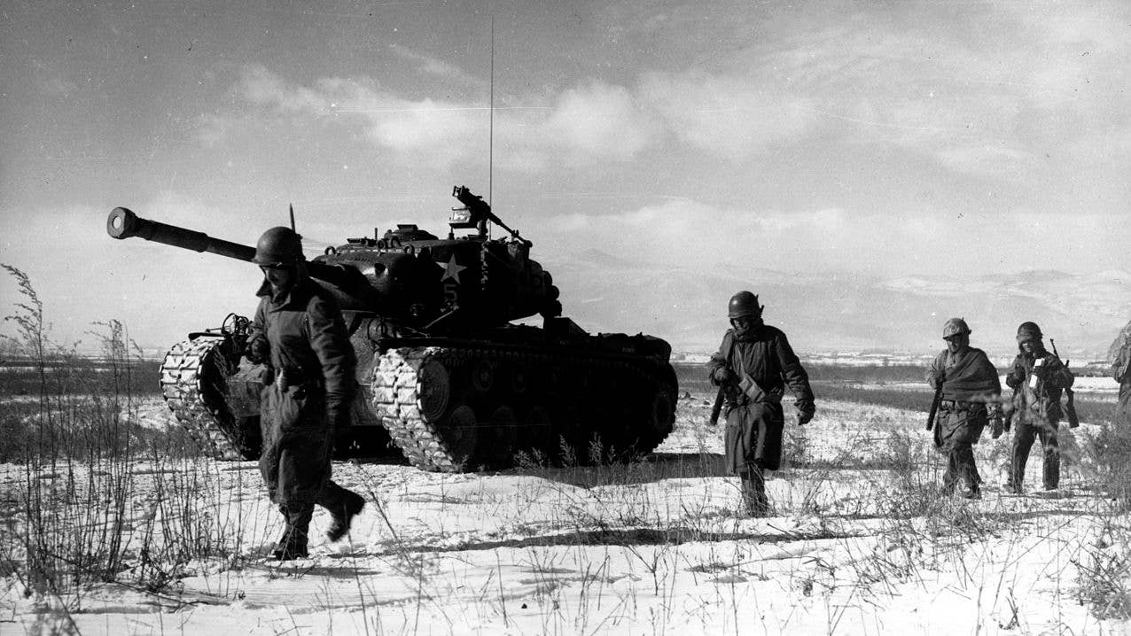 A column of the US 1st Marine Division moves through Chinese lines during its breakout from the Chosin Reservoir with a M46 Patton Medium Tank. (Photo by Corporal Peter McDonald, USMC)