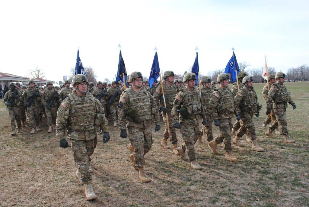 Soldiers march in a line, carrying flags