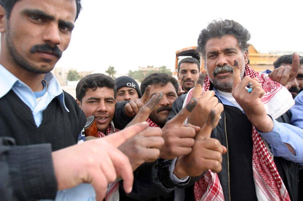 <em>Iraqi citizens hold up purple fingers to show that they voted in the January 2005 parliamentary election (USMC)</em>