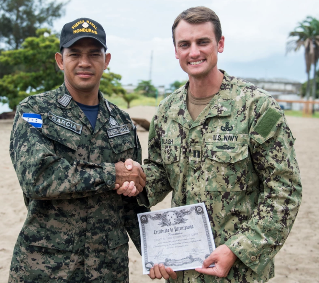 .S. Navy Lt. Mike Slagh, attached to Explosive Ordnance Disposal Mobile Unit (EODMU) 3, gives a certificate to a Honduran servicemember, attached to Buzos De Combate, during a closing ceremony in support of Southern Partnership Station 2014 (SPS-JHSV 14). (U.S. Navy photo by Mass Communication Specialist 3rd Class Andrew Schneider/Released)
