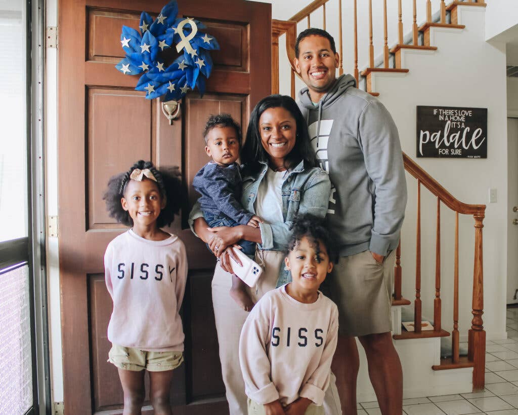 <em>Lifestyle blogger and military spouse Shakira Patterson poses with her family in front of their #BuildThanks blue wreath (Lowe's - Shakira Patterson)</em>