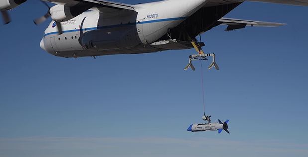 <em>A C-130 recovers an X-61 in midair (DARPA)</em>