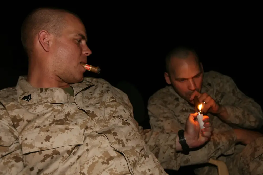 Sgt. Russell T. Ellman and Sgt. Robert W. Lauterbach, 1st Battalion, 25th Marine Regiment, Regimental Combat Team 5, gather once a week to enjoy a cigar donated to the Marines. The night allows the Marines to break away from their daily work sections and relieve a little stress. (USMC photo)