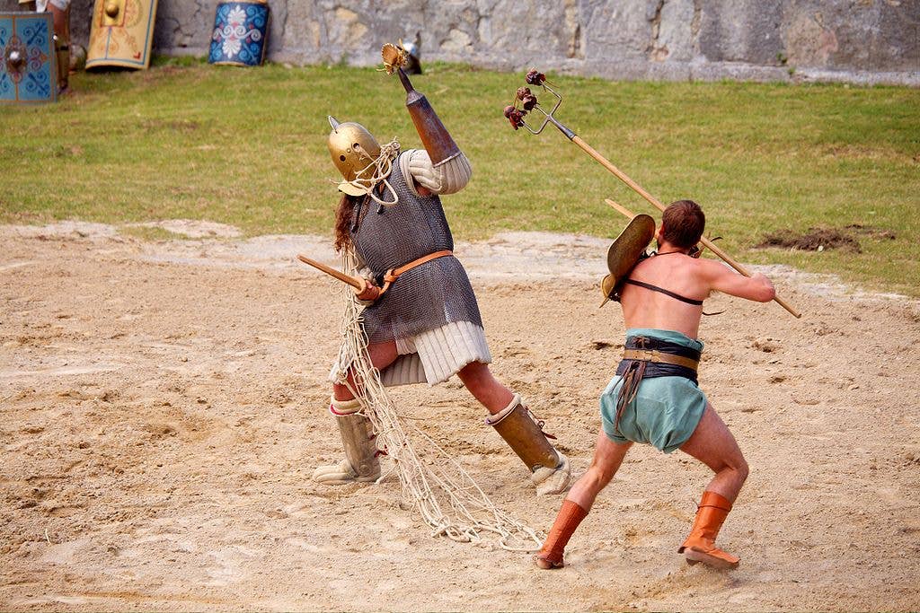 In this mock gladiatorial fight at Carnuntum, Austria, the scissor (left) is wearing a conical arm guard used to snag away the net of the retiarius (right).