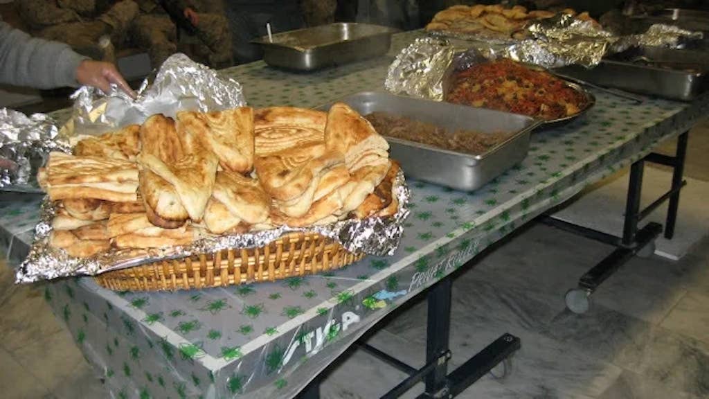 A table filled with Afghan taste treats is shown, with a large basket of Afghan bread, also known as naan, in the foreground during a recent feast held near Kabul. (Photo by Maj. Joel Anderson, DVIDS)
