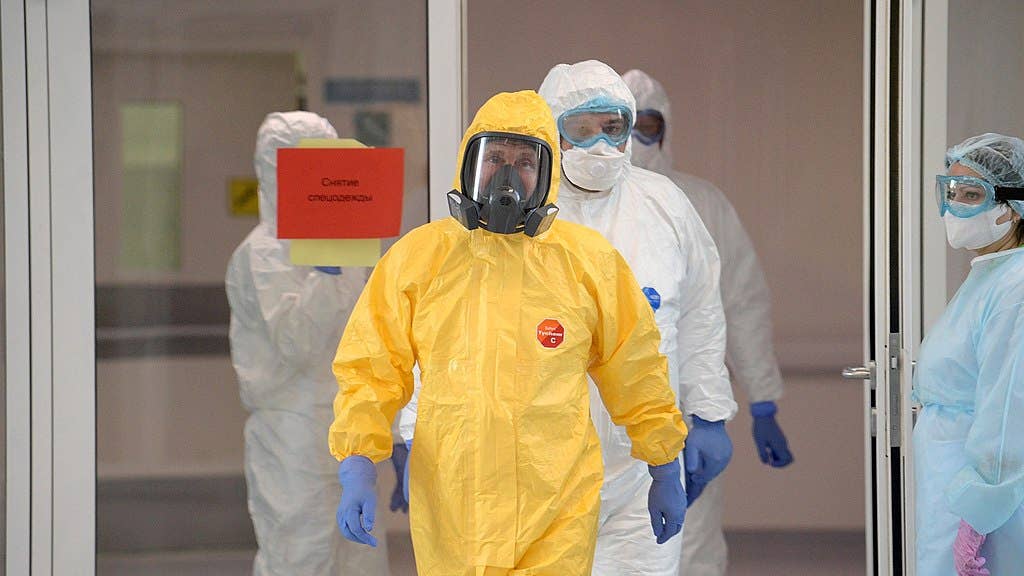 Putin (dressed in the yellow hazmat suit) exits at a Moscow hospital, 24 March 2020. (Public domain)