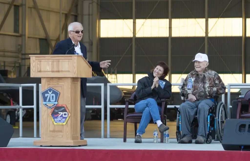 <em>Cardenas speaks next to Victoria and Chuck Yeager at the 70th Anniversary of Supersonic Flight ceremony (U.S. Air Force)</em>