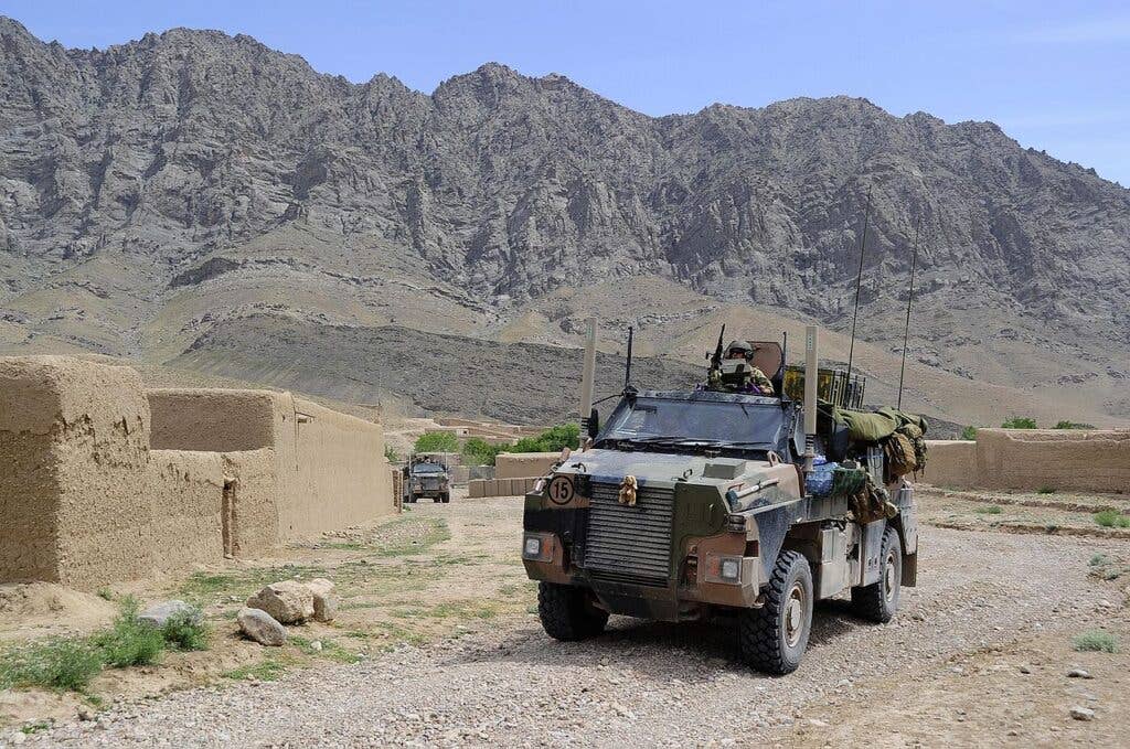 <em>Two Bushmasters pass through an Afghan village in 2010 (Australian Government DOD)</em>