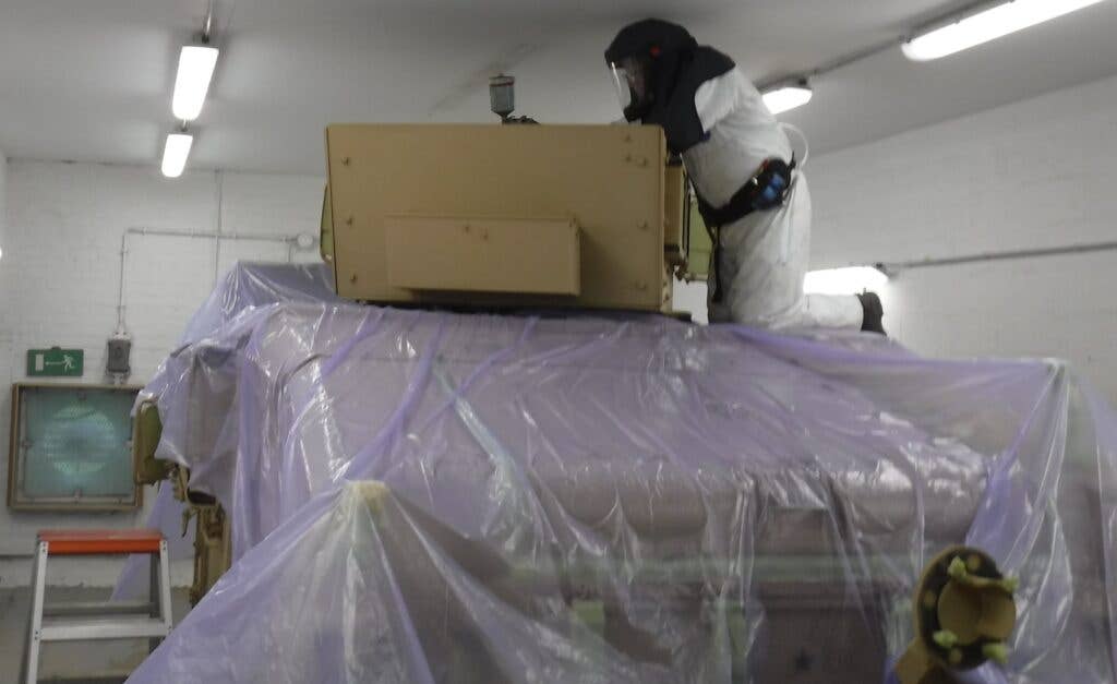 <em>A tan Humvee begins the repainting process to OD green (U.S. Army)</em>