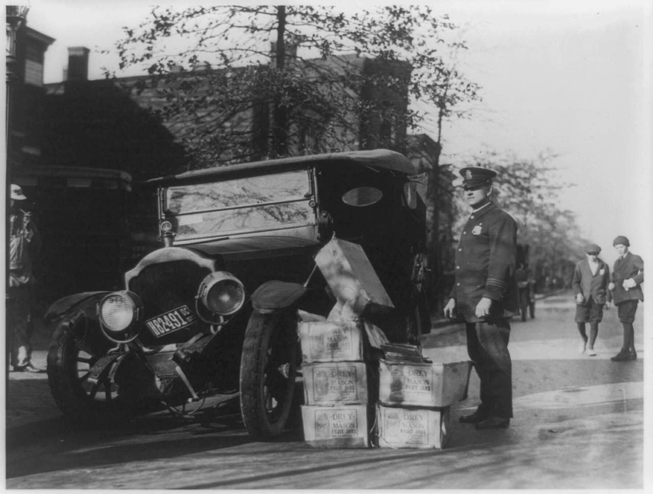 Black-and-white photograph of policeman standing alongside wrecked car and cases of liquor. Courtesy of the Prints and Photographs Division, Library of Congress, Washington, D. C.