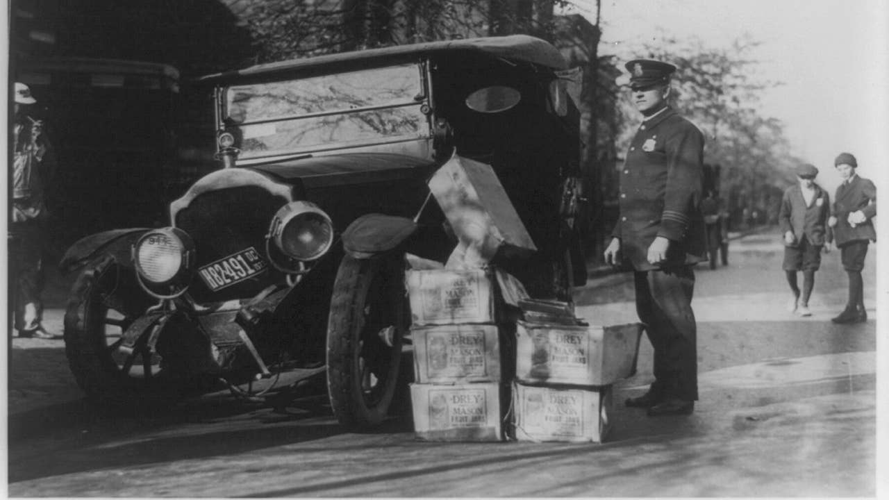 Black-and-white photograph of policeman standing alongside wrecked car and cases of liquor. Courtesy of the Prints and Photographs Division, Library of Congress, Washington, D. C.