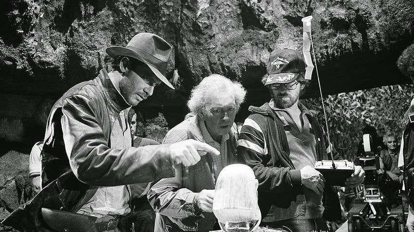Slocombe (center) on the set of <em>Raiders of The Lost Ark</em> with Harrison Ford (left) and Steven Spielberg (right). Photo courtesy of empireonline.com.