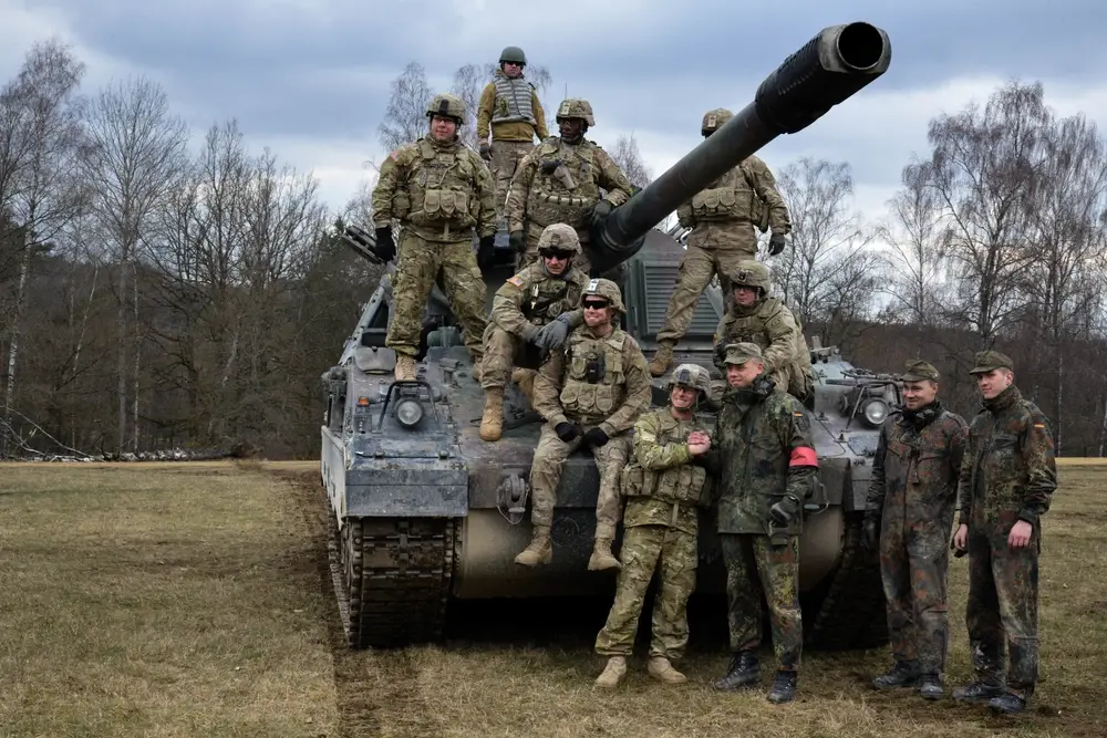 <em>US and German soldiers pose with a PzH 2000 (U.S. Army)</em>