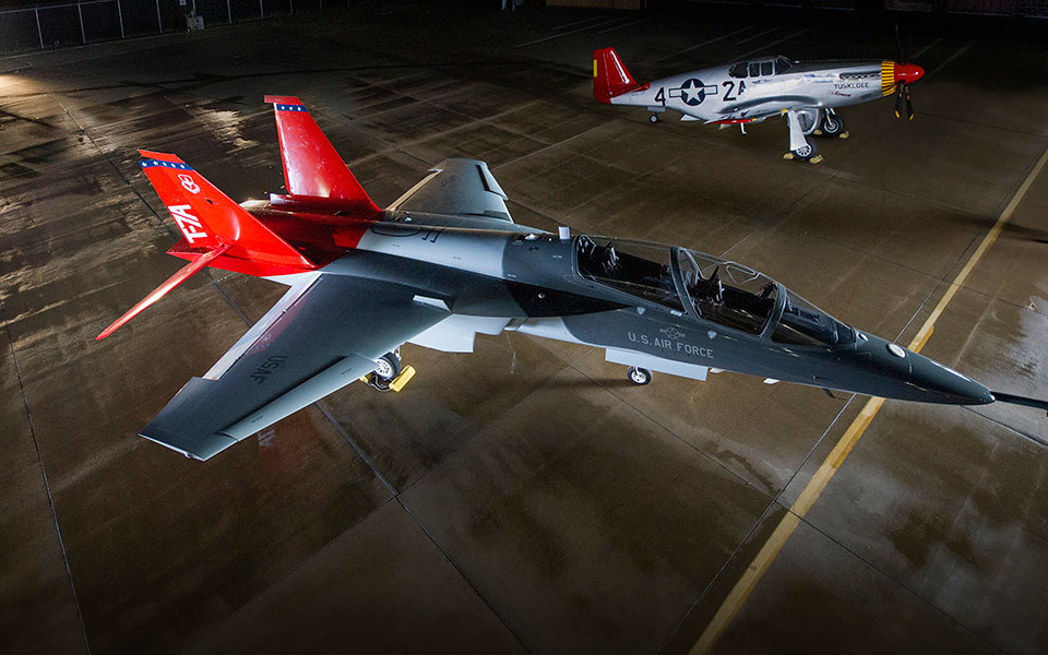 <em>The T-7A Red Hawk next to a CAF P-51C Mustang, both painted as tributes to the Tuskegee Airmen (Boeing)</em>
