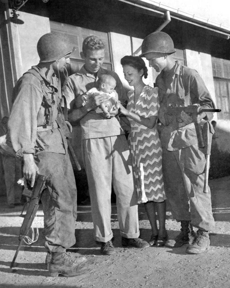 <em>Former Los Baños internees with 11th Airborne paratroopers after the raid on the prison camp (U.S. Army)</em>