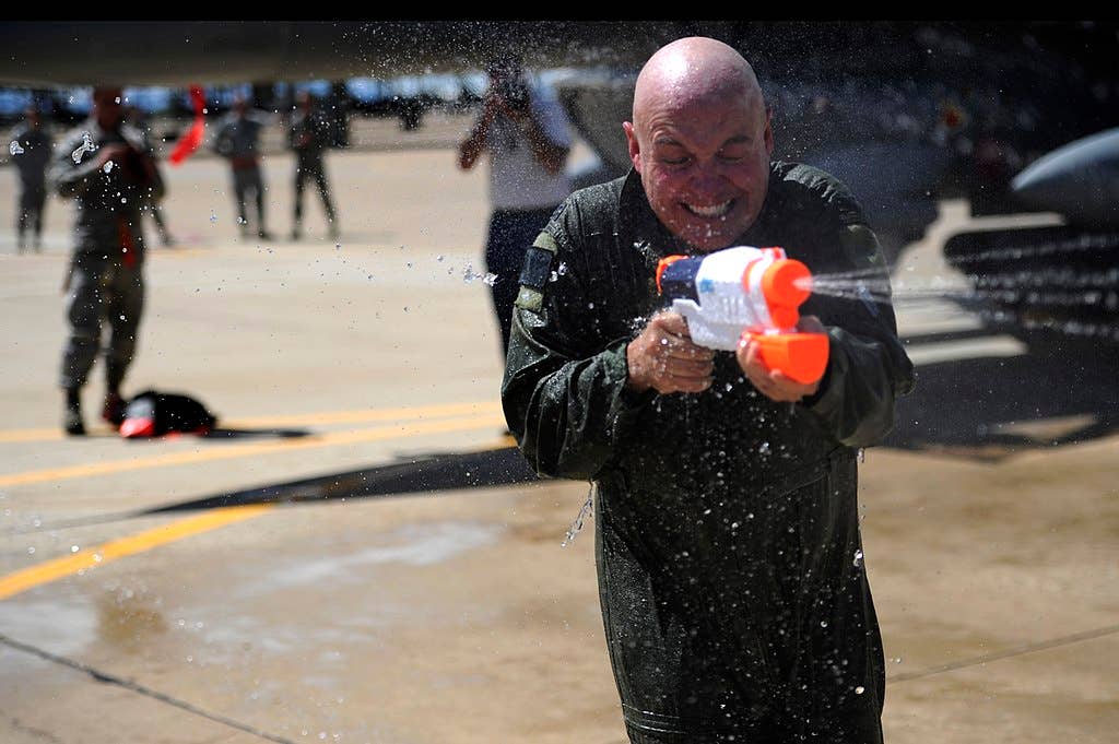 U.S. Air Force Col. Scott Long, commander 388th Fighter Wing, sprays his wife, Staci Long, with a water gun on his final flight as an Air Force airman at Hill Air Force Base, Utah, June 6, 2013. On the final flight of an Air Force career it is tradition to have a water gun battle upon the pilots exiting of their plane. (U.S. Air Force photo / Senior Airman Allen Stokes)