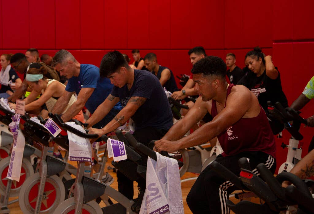 U.S. Marines and status of forces agreement personnel ride stationary bicycles during the Break the Cycle Cycle-thon at Gunner's Fitness Center, Camp Foster, Okinawa, Japan Oct. 1, 2019. The event is an 18-day event for Domestic Violence Awareness Month. (U.S. Marine Corps photo by Lance Cpl. Zachary Larsen)