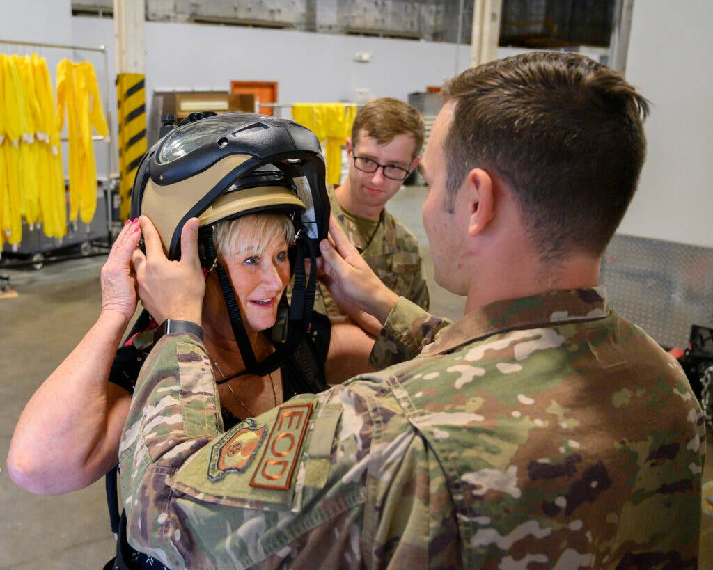 Senior Airman Johnathon Jones (foreground) and Airman 1st Class Christian Davis, of the 788th Civil Engineer Squadron’s Explosive Ordnance Disposal Flight, help Beth Duncan into a bomb suit July 14 at Wright-Patterson Air Force Base. A Leadership Dayton program member, Duncan was part of the group tour allowing participants to learn about the base’s capabilities and its community contributions. (U.S. Air Force photo by R.J. Oriez)