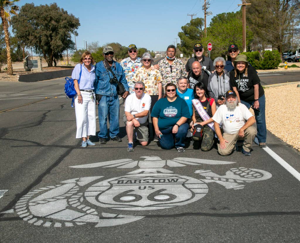 <em>Members of the California Historic Route 66 Association pose of for a photograph with the stenciled ground version of the Route 66 EGA, located on Marine Corps Logistics Base Barstow, during their tour (U.S. Marine Corps/Robert Jackson)</em>
