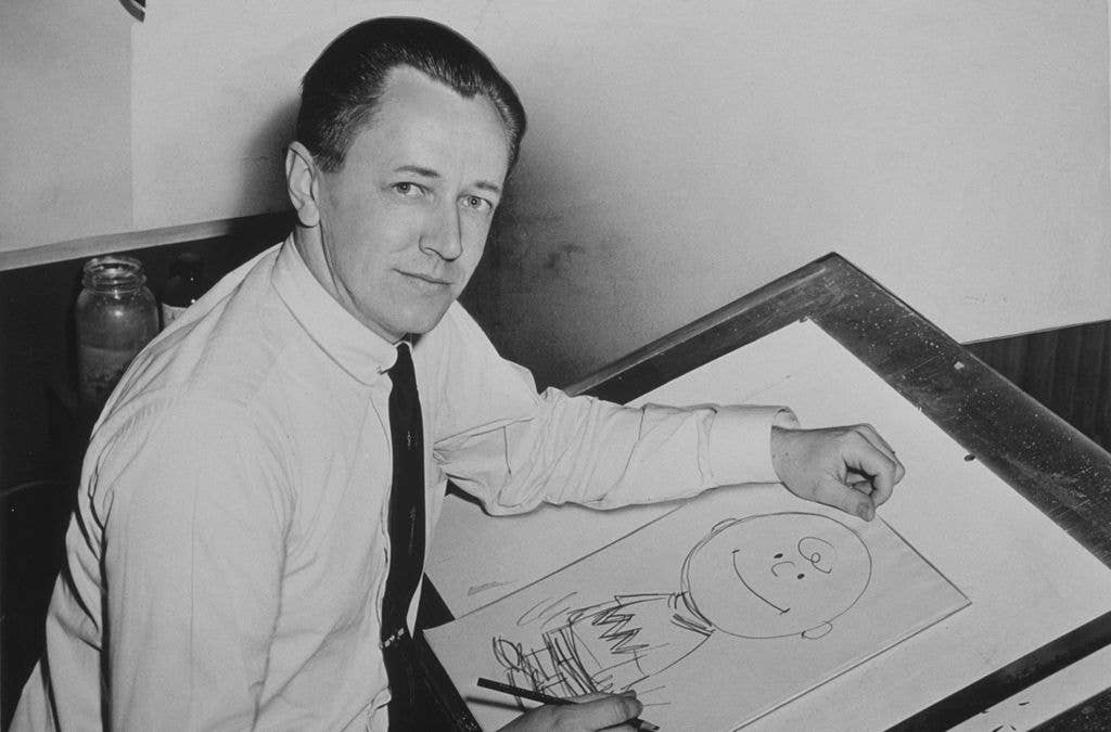 Schulz drawing <a href="https://en.wikipedia.org/wiki/Charlie_Brown">Charlie Brown</a> in 1956.