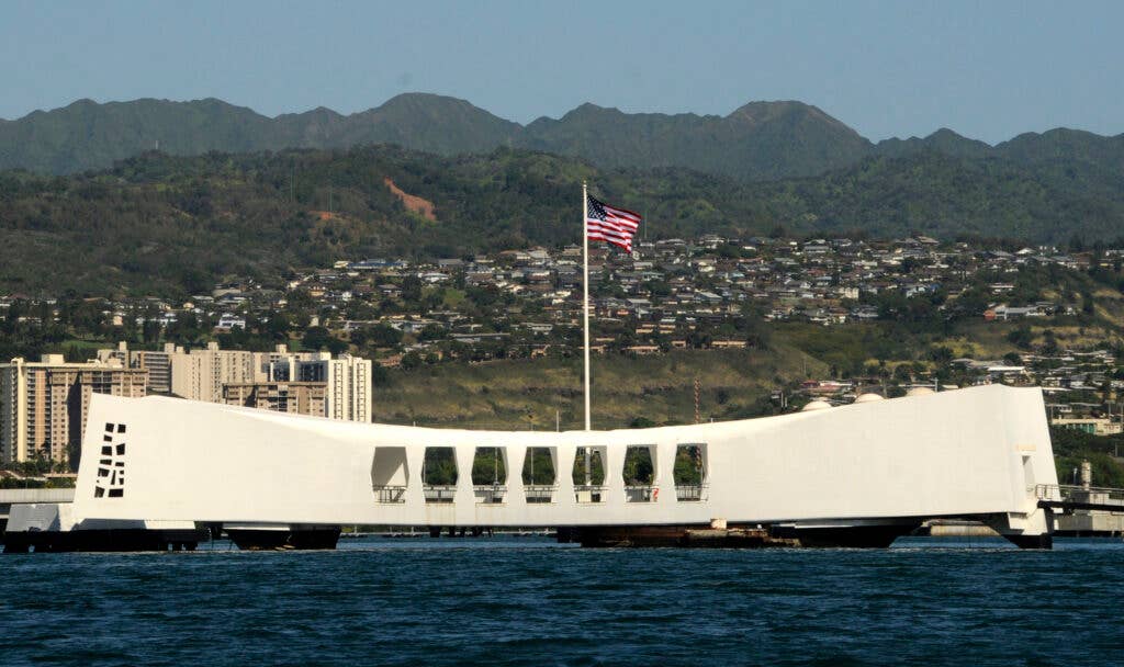 The Ensign flies over the Arizona Memorial as Sailors from Naval Station Pearl Harbor prepare to repaint and beautify the brow and deck.