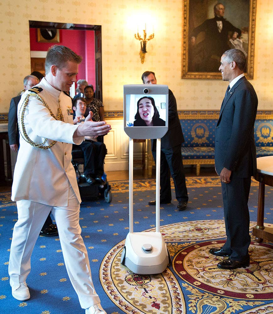 A "pulling off aide" leads Alice Wong, a disabled woman who appeared before then President Barack Obama via robot, away during a receiving line.
