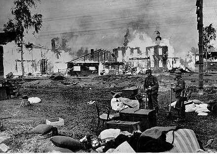 German soldiers in front of burning houses and a church, near Leningrad in 1941.
