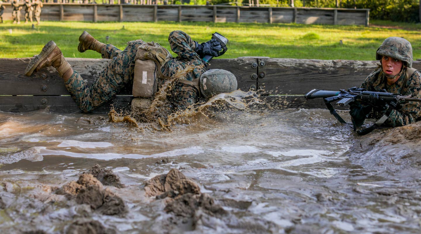 Marine recruits run through water in the Day Movement Course during Basic Warrior Training.